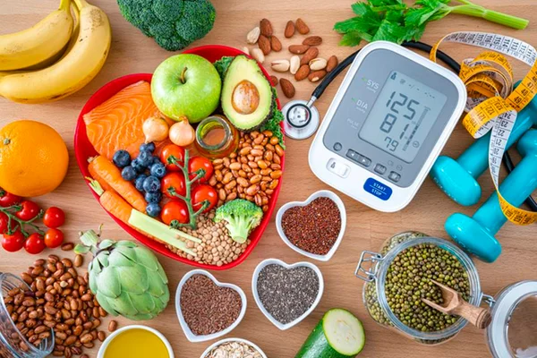 Foto de mesa com alimentos em recipientes em formato de coração e aparelho para medir a pressão - Metrópoles