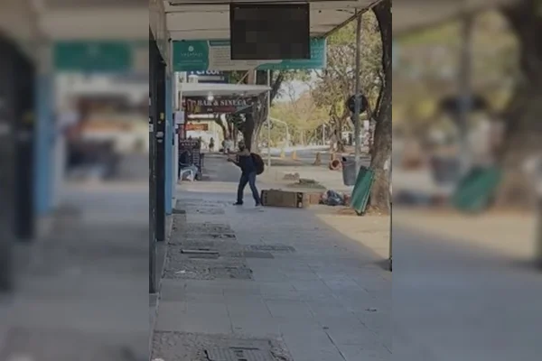 Imagem colorida de homem com camisa preta jogando pedra