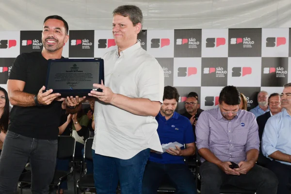 Imagem colorida mostra Tarcísio de Freitas segurando placa de Obra