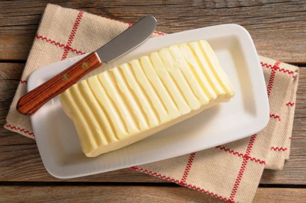 Na foto, um tablete amarelo de manteiga em cima de um recipiente branco - Metrópoles