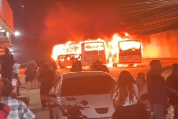 Imagem colorida, ônibus pegando fogo e pessoas ao redor - Metrópoles