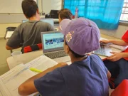 Estudante acompanha aula em escola pública da rede estadual com livro e computador