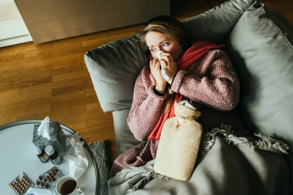 Foto colorida de mulher deitada no sofá com gripe - Médica ensina como diferenciar gripe do resfriado - Metrópoles