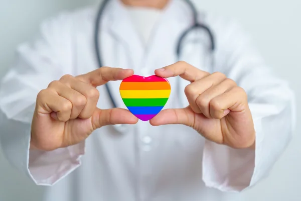 Mês do orgulho LGBTQ+ ou LGBTQIA+ e conceito de saúde. Médica com arco-íris e coração colorido para a comunidade lésbica, gay, bissexual, transgênero, queer e pansexual. Metrópoles