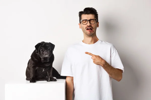 Foto colorida de tutor apontando para cachorro