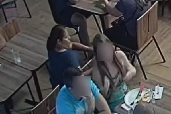 mulher sentada em mesa mexe em cadeira de outra pessoa