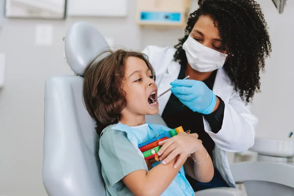 Menino no dentista. Profissinal examina dos dentes da criança. Metrópoles