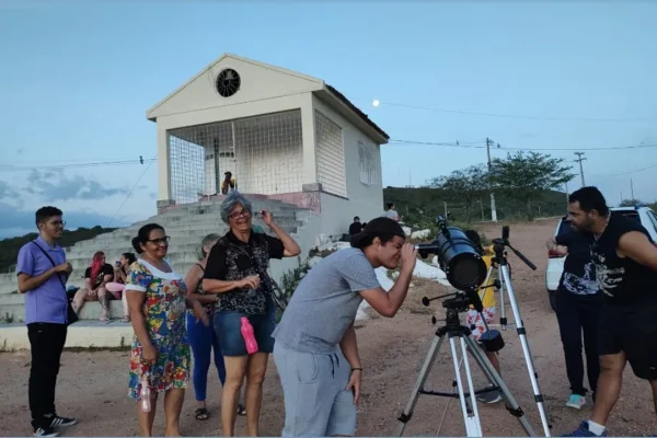 Imagem colorida mostra pessoas vendo usando telescópio no interior do Nordeste - Metrópoles