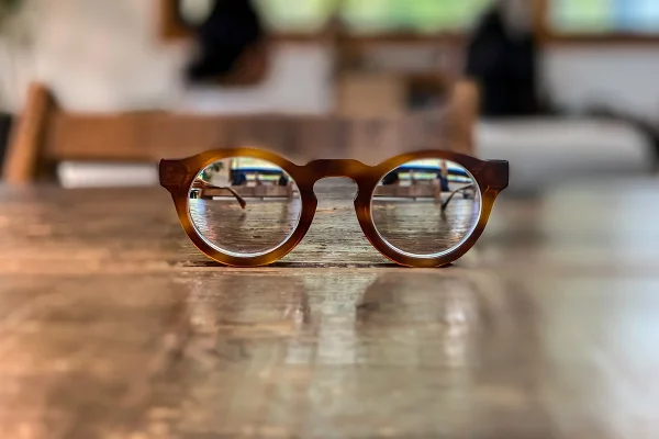 Imagem mostra um par de óculos em cima de uma mesa. O fundo está desfocado, mas as lentes de miopia estão nítidas - Metrópoles