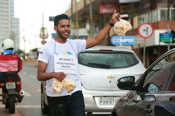 Jovem vende biscoito no semáforo para pagar dívida na faculdade