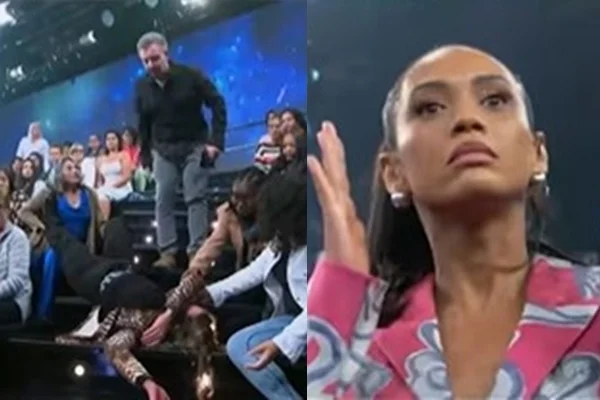 Mulher caída em escada e pessoas olhando ao redor no canto esquerdo da imagem. No canto direito, mulher negra está com cara assustada e mão ao lado do rosto. Ela usa um blazer rosa com azul