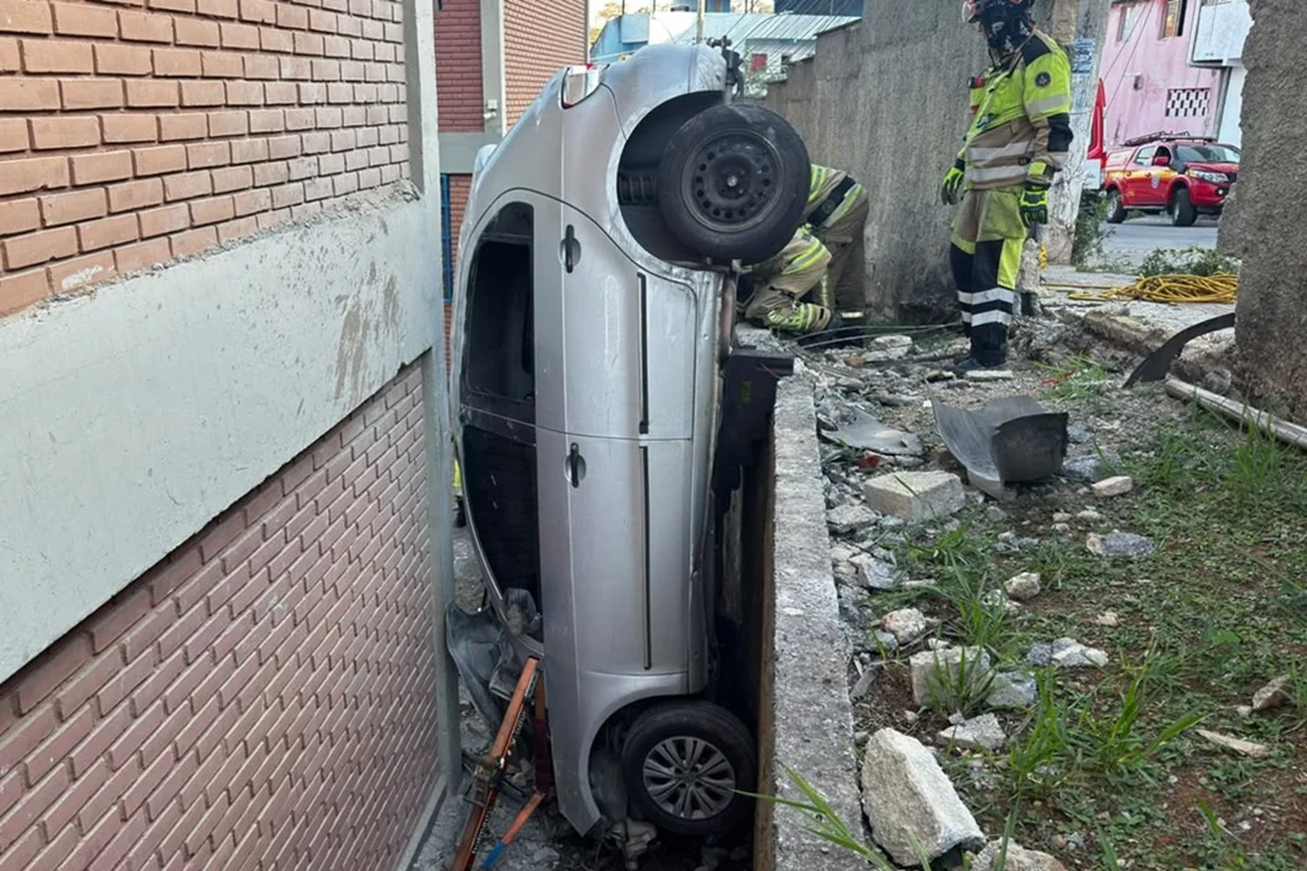 BH: carro bate, derruba muro de escola e fica pendurado em desnível