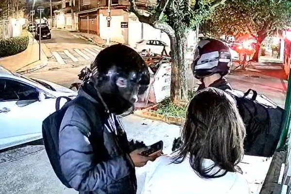 Imagens de câmeras de segurança mostram um suspeito aguardando na rua e, ao ver a mulher, se aproxima de moto, saca a arma e anuncia assalto - Metrópoles