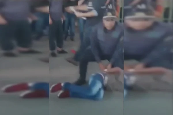 Policial militar ajoelhado em cima de aluno