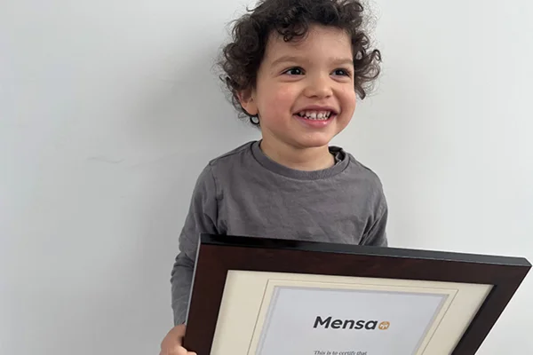 Imagem colorida de menino exibindo placa de sociedade de QI alto - Metrópoles
