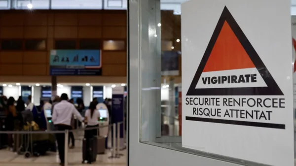 Imagem colorida de passageiros em fila para fazer o check-in ao lado de uma placa de advertência Vigipirate (à direita) que diz "segurança reforçada, risco de ataque terrorista" no aeroporto internacional de Caiena, Guiana Francesa, em 24 de março de 2024 França - Metrópoles