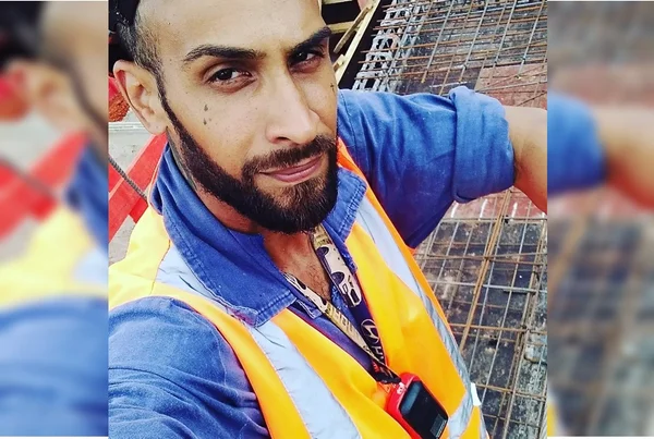 Imagem colorida mostra homem com barba escura vestido com camisa azul e colete amarelo - Metrópoles