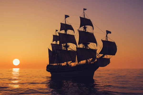Imagem de navio pirata em mar com o pôr do sol ao fundo - Metrópoles