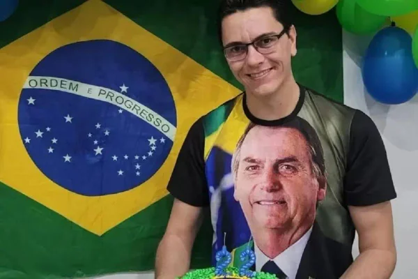 foto colorida de Carlos Victor de Carvalho, o CVC, com bandeira do Brasil ao fundo e camisa com foto de Jair Bolsonaro