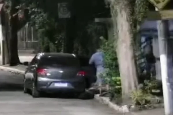 Imagem colorida de carro cinza estacionado e um homem saindo. Metrópoles