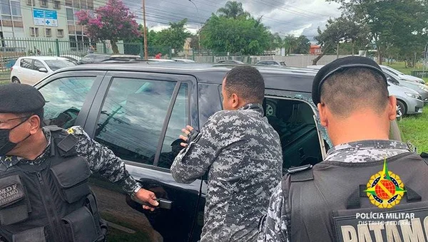 Três homens fardados acessam carro escuro por janela quebrada