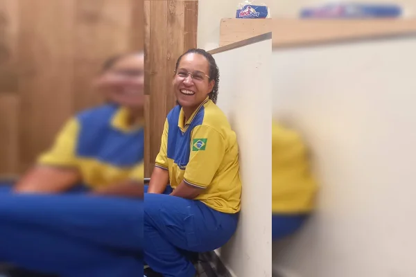 Foto colorida mulher agachada com roupa do Correios