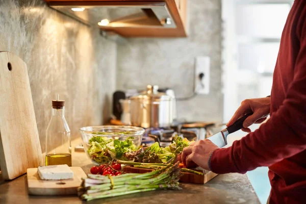 Foto colorida de um mulher cortando alimentos - Metrópoles