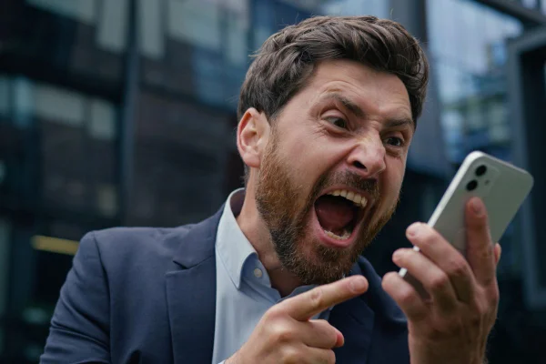 Homem de terno gritando e apontando o dedo para a tela do celular
