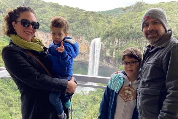Foto colorida de adultos com duas crianças com uma cachoeira no fundo - Metrópoles.
