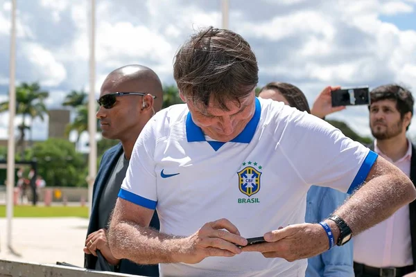 foto colorida de jair bolsonaro olhando para celular