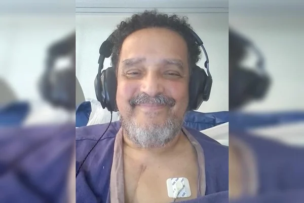 Homem com fone e sorrindo internado em hospital