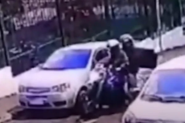 Imagem colorida de suspeitos executando homem dentro de carro. Metrópoles