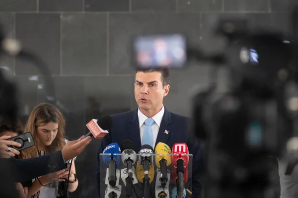 homem de terno atrás de microfones