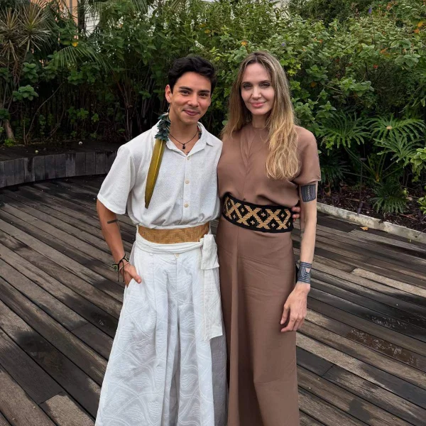 A imagem mostra a atriz Angelina Jolie e o estilista MAurício Duarte sorrindo para a foto