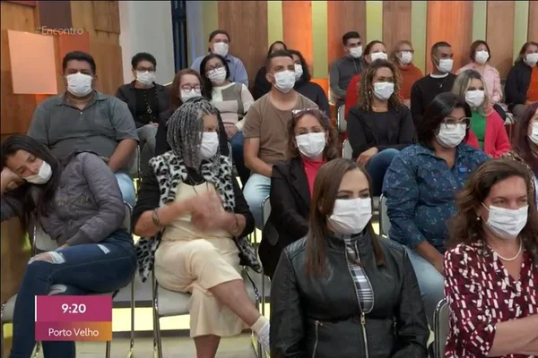 Em meio à plateia do programa "Encontro", na TV Globo, mulher dorme escorada na parede, no canto inferior esquerdo - Metrópoles