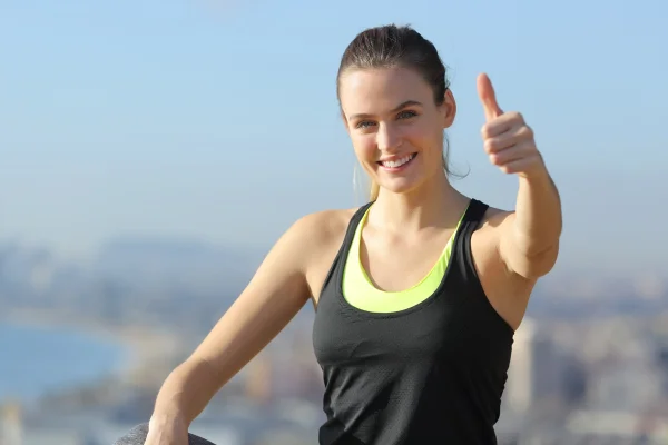 Foto colorida de mulher sentada acenando. Ela está sorrindo estilo de vida - Metrópoles