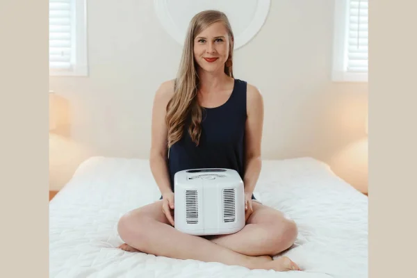 mulher sentada na cama segurando equipamento