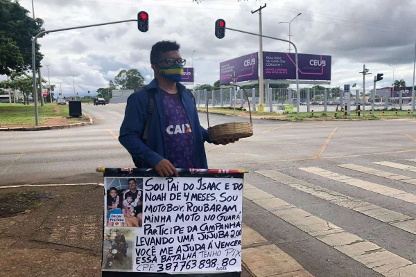 Homem segura placa e cesta com jujubas em semáforo