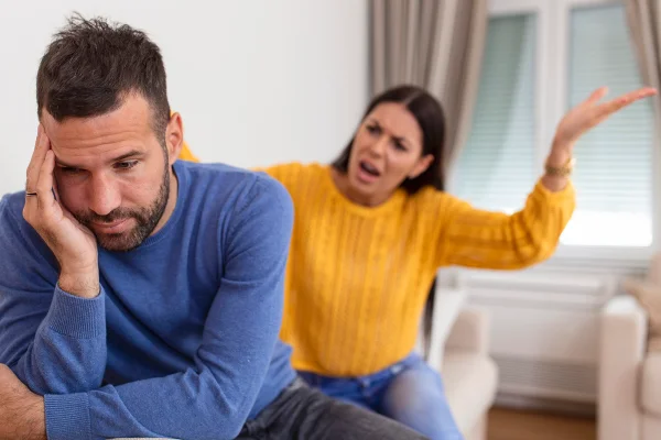 Foto colorida de homem vestido de azul, mulher de amarelo. O homem está com cara de arrependido enquanto a mulher está com os braços ao alto, sinônimo de indignação - Metrópoles.