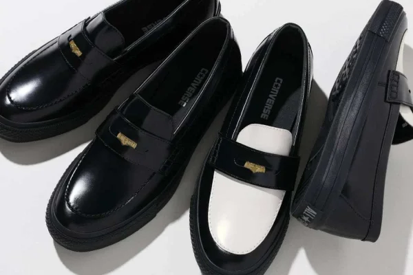 A imagem mostra sapatos sociais pretos com detalhes brancos e dourados