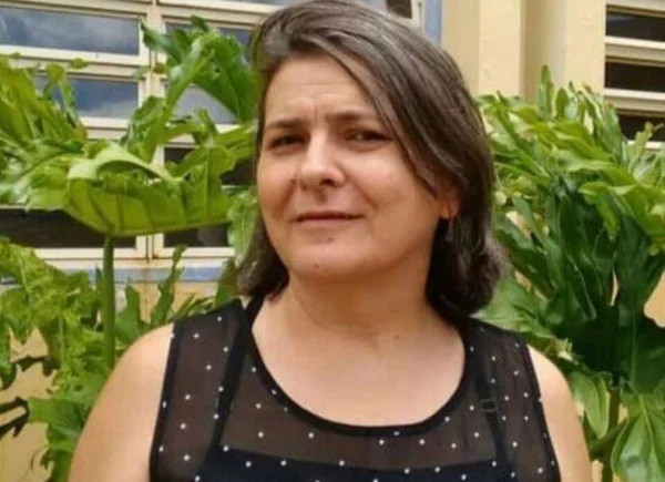 Mulher de cabelo curto e blusa preta sorrindo para foto