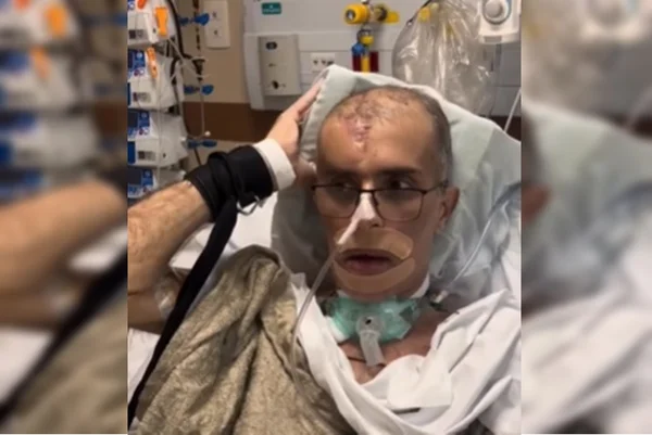 Imagem colorida de homem na cama de um hospital com aparelhos e segurando um travesseiro