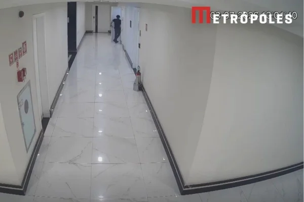 Foto colorida do momento em que homem entra em banheiro feminino para instalar celular embaixo de pia, em prédio comercial de Santos, litoral de São Paulo.