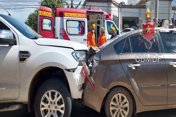 Camionete Branca após colisão com sedan marrom. Ao fundo ambulância dos bombeiros.
