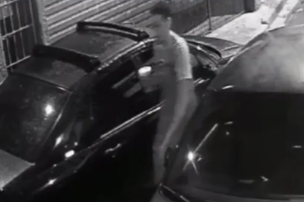 Imagem em preto e branco de homem quebrando retrovisor. Metrópoles