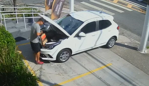 Em foto colorida outro criminoso abre capô de carro - Metrópoles