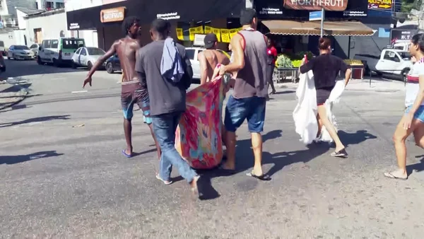 corpo sendo carregado por quatro homens em operação Complexo do Alemão