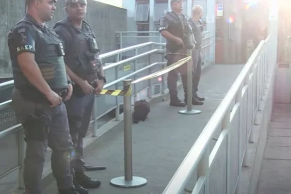 Imagem colorida de policiais militares encostados em estação e uma arma no chão. Metrópoles