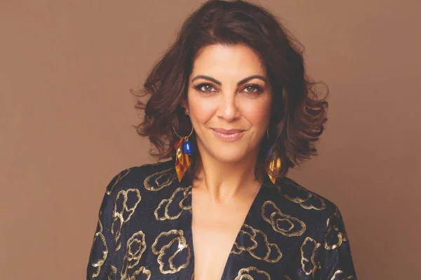 Foto colorida de Thalita Rebouças usando brinco, roupa azul e sorrindo - Metrópoles
