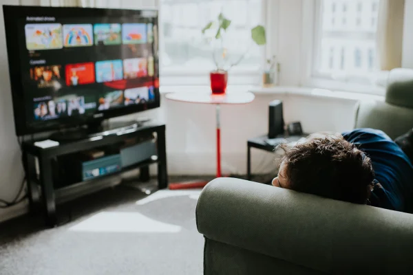 Imagem colorida de homem deitado assistindo televisão